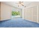 Bedroom with blue carpet, ceiling fan, double door closet and sliding glass door to a pool area at 1402 E Mimosa Dr, Plant City, FL 33563