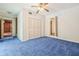 Bedroom with blue carpet, ceiling fan and double door closet providing ample storage space at 1402 E Mimosa Dr, Plant City, FL 33563