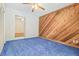 Bedroom with blue carpet, wood wall accent, ceiling fan and view of an adjacent room through folding door at 1402 E Mimosa Dr, Plant City, FL 33563