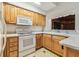 Well-lit kitchen featuring wooden cabinets, white appliances, and tile flooring at 1402 E Mimosa Dr, Plant City, FL 33563