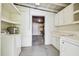 View of a laundry room with white washer and dryer, open shelving, and utility sink at 1402 E Mimosa Dr, Plant City, FL 33563