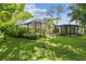 Lush backyard with green grass, landscaping, and a screened-in pool and patio area at 1402 E Mimosa Dr, Plant City, FL 33563