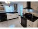 Updated kitchen featuring white cabinetry, black countertops and appliances, and tile flooring at 1583 Eunice Ln, Clearwater, FL 33756