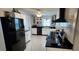 Modern kitchen with black appliances, white cabinets, granite counters, and stylish marble flooring at 1583 Eunice Ln, Clearwater, FL 33756
