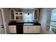 Bright kitchen features white cabinets, black countertops and appliances, and built-in display shelving at 1583 Eunice Ln, Clearwater, FL 33756