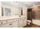 Bathroom featuring double sinks with wood cabinets and a tiled shower with a patterned curtain at 19209 Long Lake Ranch Blvd, Lutz, FL 33558