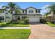 Charming two-story home showcasing lush landscaping, a brick driveway, and a welcoming facade at 19209 Long Lake Ranch Blvd, Lutz, FL 33558