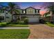 Beautiful two-story home featuring lush landscaping, brick driveway, and a welcoming facade at sunset at 19209 Long Lake Ranch Blvd, Lutz, FL 33558