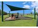 Community playground featuring a slide and swingset protected by a shade structure, surrounded by lush green grass and scenic views at 19209 Long Lake Ranch Blvd, Lutz, FL 33558