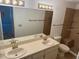 Bright bathroom featuring double sinks, tile floors, and a tiled walk-in shower with a bench at 1922 Blue Sage Ct, Brandon, FL 33511