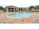 Community pool with paver deck, covered seating area, and well-maintained landscaping at 1976 Marlington Way, Clearwater, FL 33763
