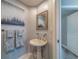 Powder room showcasing a pedestal sink, decorative towels, modern artwork, and a doorway to another room at 2 Seaside Ln # 801, Belleair, FL 33756