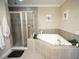 Elegant bathroom featuring a soaking tub, glass shower, and neutral tile at 2575 W Platt St, Tampa, FL 33609