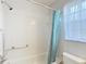 Bathroom with white tiled shower, shower curtain, window and hand rail at 2937 Stilwell Ct, New Port Richey, FL 34655