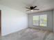 Bright bedroom featuring neutral carpet, ceiling fan, and a window with natural light at 2937 Stilwell Ct, New Port Richey, FL 34655
