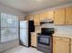 Cozy kitchen with wood cabinets, stainless steel appliances, and a bright window at 2937 Stilwell Ct, New Port Richey, FL 34655