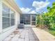 View of the brick patio featuring a screened enclosure, native Florida plants, and an external air conditioning unit at 2937 Stilwell Ct, New Port Richey, FL 34655