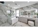 Luxurious bathroom featuring marble walls, a soaking tub, a glass-enclosed shower, and dual sinks at 32203 Mahogany Valley Dr, Wesley Chapel, FL 33543