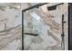 Elegant shower with marble tile, glass doors, and a modern shower head fixture at 32203 Mahogany Valley Dr, Wesley Chapel, FL 33543