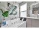 Close-up of a soaking tub with marble tile walls and a modern vanity at 32203 Mahogany Valley Dr, Wesley Chapel, FL 33543