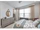 Bright bedroom with a ceiling fan, large window with blinds, and neutral gray dresser with a round mirror at 32203 Mahogany Valley Dr, Wesley Chapel, FL 33543