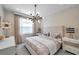 Stylish bedroom with a tufted headboard, patterned wallpaper, and modern chandelier at 32203 Mahogany Valley Dr, Wesley Chapel, FL 33543