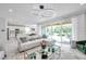 Bright living room featuring modern circular lighting fixture, large windows, and sliding glass doors to the backyard at 32203 Mahogany Valley Dr, Wesley Chapel, FL 33543