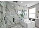 Close-up of the luxurious glass-enclosed shower with marble walls and modern fixtures at 32203 Mahogany Valley Dr, Wesley Chapel, FL 33543