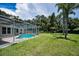 Expansive backyard with a screened pool enclosure and a lush green lawn at 3411 Glossy Ibis Ct, Palm Harbor, FL 34683