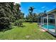 Spacious backyard with lush green grass and a screened-in pool, providing a private outdoor oasis at 3411 Glossy Ibis Ct, Palm Harbor, FL 34683
