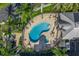 Aerial view of a kidney bean shaped pool with lounge chairs, spa and covered area at 423 150Th Ave # 1501, Madeira Beach, FL 33708