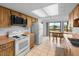 Efficient kitchen featuring wood cabinets, white appliances, a tile backsplash, and a view into the dining area at 4279 Newport Dr, Hernando Beach, FL 34607
