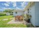 Backyard with a stone patio set with an outdoor dining area, greenery and view of the exterior of the home at 4518 Ashmore Dr, Tampa, FL 33610