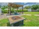 Backyard featuring a fire pit, outdoor seating beneath a pergola, and lush greenery at 4518 Ashmore Dr, Tampa, FL 33610