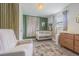 Bedroom featuring a baby crib, glider chair, dresser, green accent wall, and stylish floral area rug at 4518 Ashmore Dr, Tampa, FL 33610