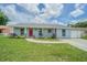 Charming single-story home with a red front door, lush lawn, and well-maintained landscaping at 4518 Ashmore Dr, Tampa, FL 33610