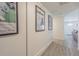 Hallway with grey wood-style tile and decorative framed posters on white walls and a view to the home's entrance at 4518 Ashmore Dr, Tampa, FL 33610