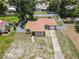 Aerial view of the property features a fenced-in yard, well-maintained lawn, paved driveway, and lush green trees at 525 38Th S St, St Petersburg, FL 33711
