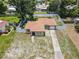 Aerial view of the property features a fenced-in yard, well-maintained lawn, paved driveway, and lush green trees at 525 38Th S St, St Petersburg, FL 33711