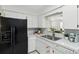 Bright white kitchen featuring a black refrigerator, stainless steel sink, and modern appliances at 6119 31St N Ave, St Petersburg, FL 33710