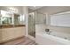 Bathroom featuring a soaking tub, large vanity with stone countertop, and glass shower at 6513 Sand Shore Ln, New Port Richey, FL 34652
