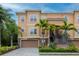 Beautiful townhome showcasing a two-car garage and meticulous landscaping with mature palm trees at 6513 Sand Shore Ln, New Port Richey, FL 34652