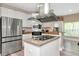 Bright kitchen featuring stainless steel appliances, granite counters, a cooktop island, and white cabinetry at 6513 Sand Shore Ln, New Port Richey, FL 34652