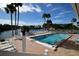 Beautiful outdoor swimming pool surrounded by palm trees and waterfront views on a sunny day at 6513 Sand Shore Ln, New Port Richey, FL 34652