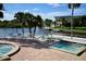 Outdoor pool area with spa, complete with lounge chairs, palm trees, and waterfront views at 6513 Sand Shore Ln, New Port Richey, FL 34652