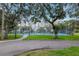 Community tennis courts with bright blue surface surrounded by green lawns and mature trees at 6513 Sand Shore Ln, New Port Richey, FL 34652