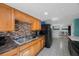 Well-lit kitchen with wood cabinets, a stainless steel sink, and a modern backsplash at 6834 Mesa Verde St, Port Richey, FL 34668