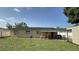 Back exterior view of the house and a covered porch, showing it has a large grassy yard, storage shed, and AC units at 7206 Reindeer Rd, Tampa, FL 33619