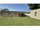 Back exterior view of the house and a covered porch, showing it has a large grassy yard, storage shed, and AC units at 7206 Reindeer Rd, Tampa, FL 33619