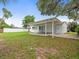 Expansive backyard with a covered patio, lush lawn, and a white fence offering privacy, perfect for outdoor gatherings at 7571 Ridge Rd, Seminole, FL 33772